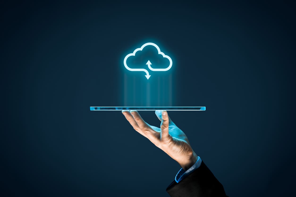 Una mano sostiene una tableta transparente con un ícono de nube brillante encima, que simboliza la computación en la nube y el almacenamiento de datos.